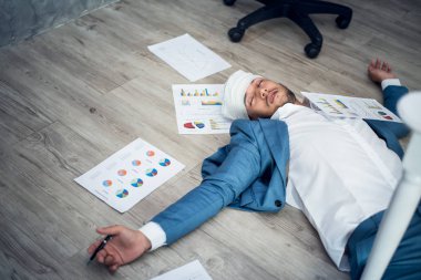 Takım elbise içinde yerde bilinçsizce yatan iş adam