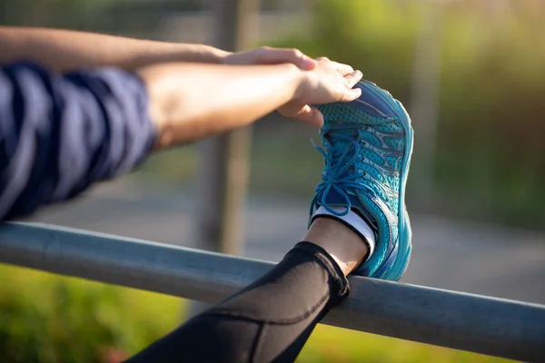 Runner woman stretching leg muscle preparing in green park at su