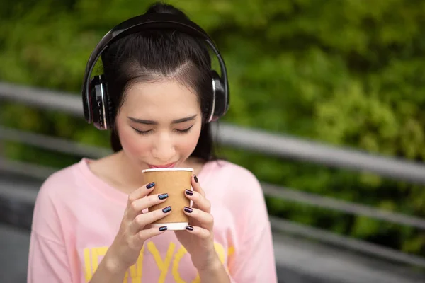 Joven mujer asiática disfrutar escuchando música con auriculares y h — Foto de Stock