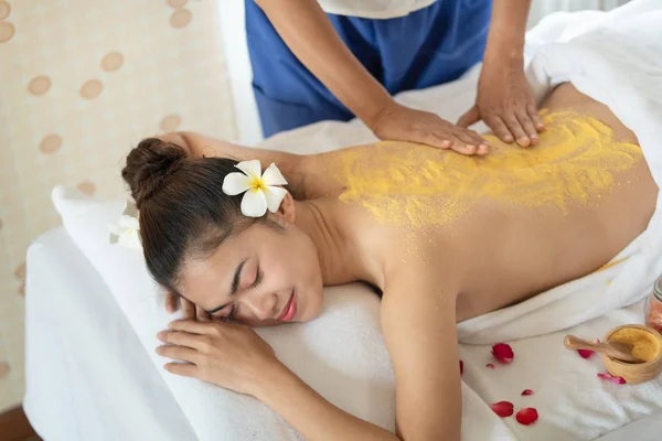 Beautiful Asian woman having exfoliation treatment with body scr