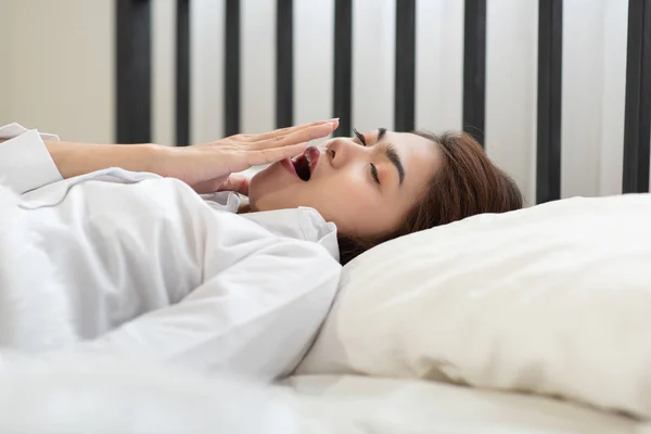 Young Asian woman yawning while waking up in the morning