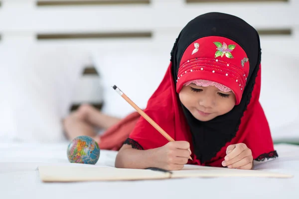 Young muslim girl writing a book, islamic child do homework at h