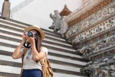 Genç Asyalı kadın turist kamerayla fotoğraf çekiyor.