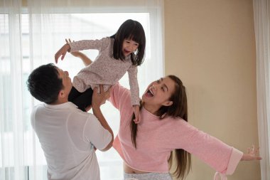 Baba, anne ve çocuklar eğleniyor ve yatak odasında oynuyorlar, mutlu Asyalı aile evde.