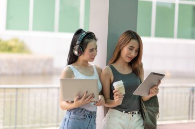 Kampüste dizüstü bilgisayarla okuyan ve dijital tablet, eğitim konsepti kullanan Asyalı genç öğrencilerin portresi