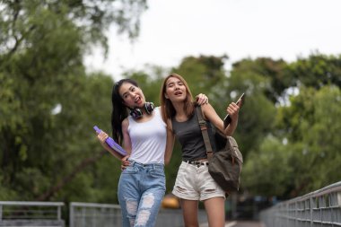 Kampüste yürürken konuşan iki genç Asyalı üniversite öğrencisi.