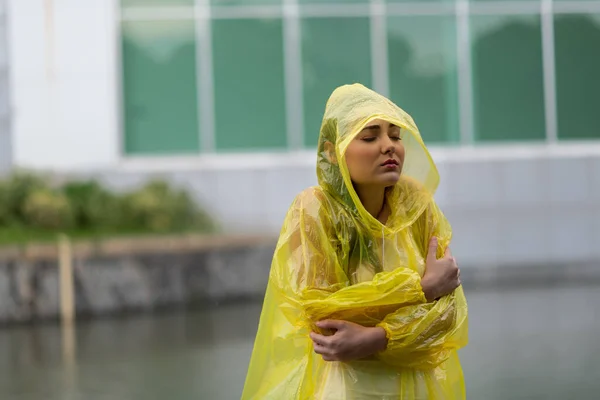 Portrait of the women wearing yellow raincoat while raining in rainy season