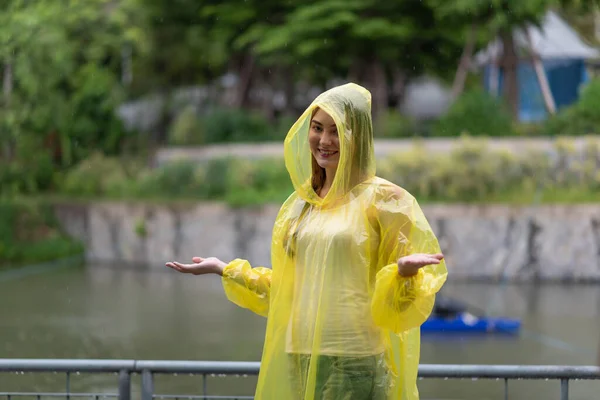 Portrait of the women wearing yellow raincoat while raining in rainy season