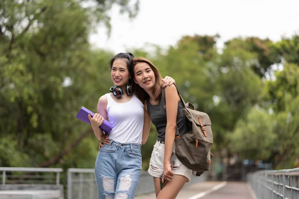 Kampüste yürürken konuşan iki genç Asyalı üniversite öğrencisi.