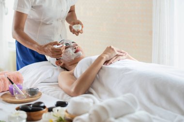 Güzellik salonunda maske takmış genç Asyalı kadın, eğleniyor ve dinleniyor, cilt bakımı ve sağlık hizmetleri kavramı