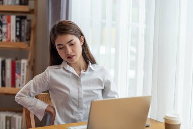 İş kadını portresi, bilgisayarın kötü bir pozisyonda oturmasından sonra omurgasında ağrı hisseder.