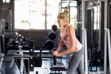 Güçlü bir kadın spor salonunda ağırlık plakasıyla egzersiz yapıyor spor salonunda egzersiz yapıyor.