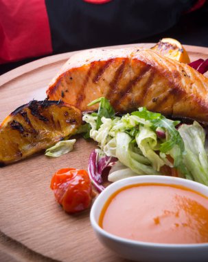 Ahşap oyun tahtası salata ile servis ızgara somon dilimi