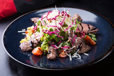 Alarmdan karanlık bir tabağa dilimlenmiş sebze salata ile servis edilir