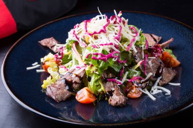 Alarmdan karanlık bir tabağa dilimlenmiş sebze salata ile servis edilir