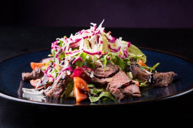 Alarmdan karanlık bir tabağa dilimlenmiş sebze salata ile servis edilir