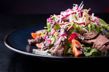 Alarmdan karanlık bir tabağa dilimlenmiş sebze salata ile servis edilir