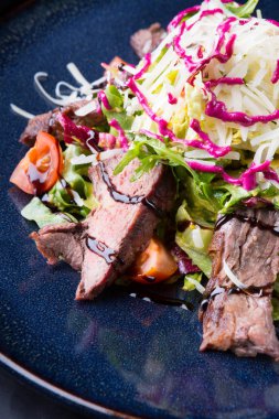 Alarmdan karanlık bir tabağa dilimlenmiş sebze salata ile servis edilir