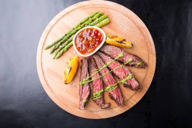 Ahşap tahta üzerinde kuşkonmaz ile servis sığır eti biftek dilimlenmiş