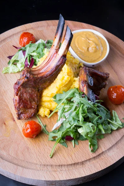 Grilled lamb meat served with salad on a wooden board