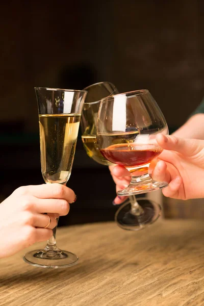 Women\'s hands cheering with wine glasses at the table