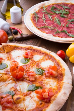 İki farklı pizza taze pişmiş ve ahşap masaya servis