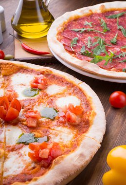 İki farklı pizza taze pişmiş ve ahşap masaya servis