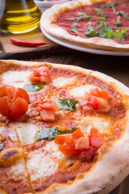 İki farklı pizza taze pişmiş ve ahşap masaya servis