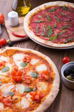İki farklı pizza taze pişmiş ve ahşap masaya servis
