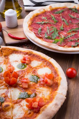 İki farklı pizza taze pişmiş ve ahşap masaya servis