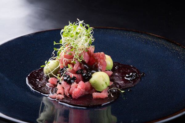 Raw tuna salad tartare served on a black elegant plate