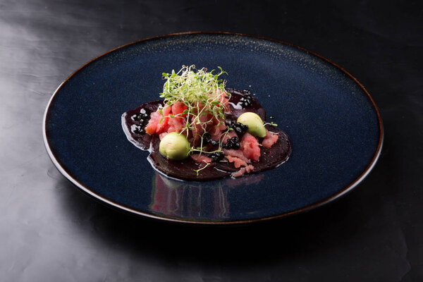 Raw tuna salad tartare served on a black elegant plate