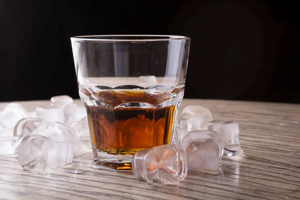Whiskey glass on a bar counter with ice cubes
