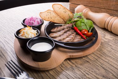 Acı biber ve sebzeyle servis edilen ateş edilmiş sığır dili.