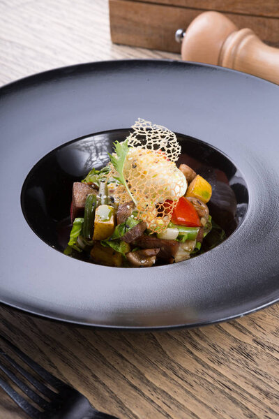 Warm beef salad served in a black plate