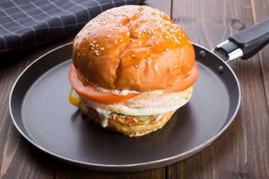 Ahşap masa üzerinde küçük bir tavada servis hamburger