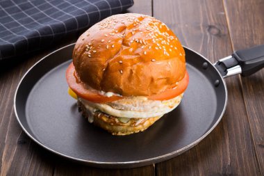 Ahşap masa üzerinde küçük bir tavada servis hamburger