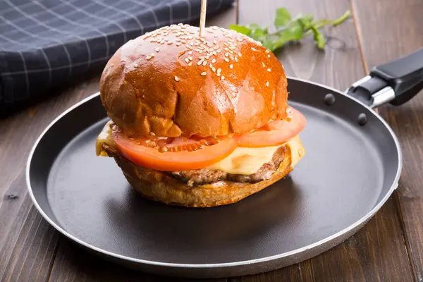 Ahşap masa üzerinde küçük bir tavada servis hamburger