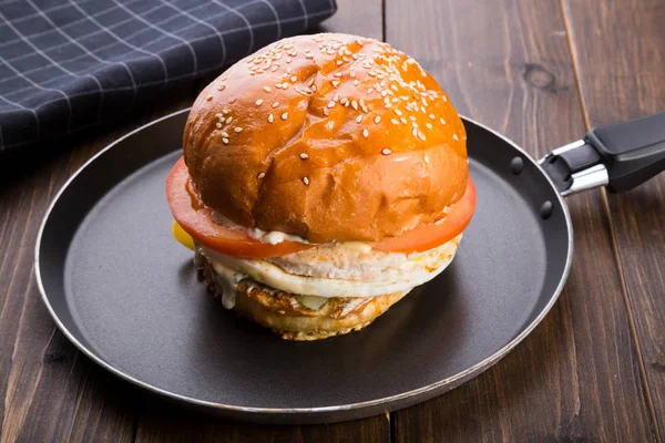 Ahşap masa üzerinde küçük bir tavada servis hamburger