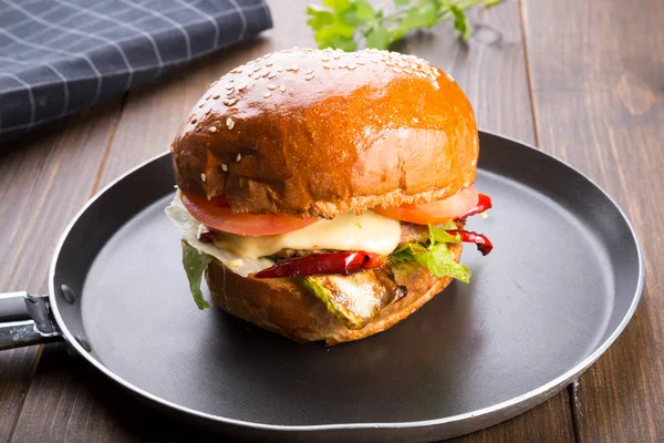 Ahşap masa üzerinde küçük bir tavada servis hamburger