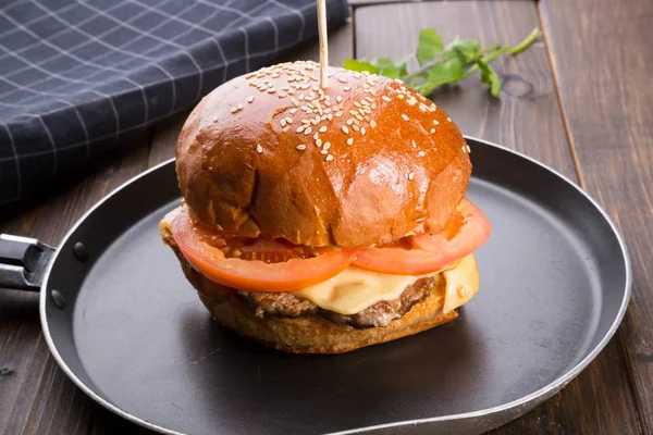 Ahşap masa üzerinde küçük bir tavada servis hamburger
