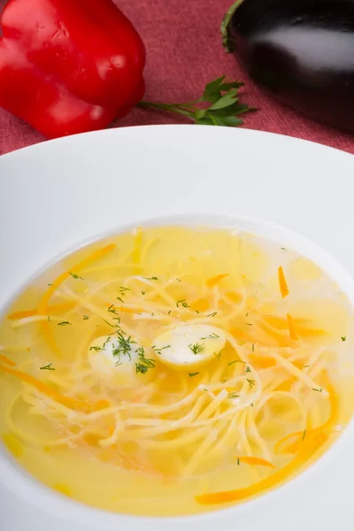Желтый суп с лапшой и перепелиным яйцом в белой тарелке — стоковое фото