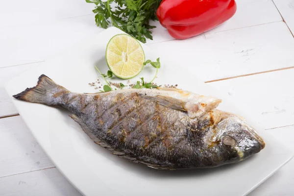 Pescado dorado a la parrilla servido en un plato blanco —  Fotos de Stock