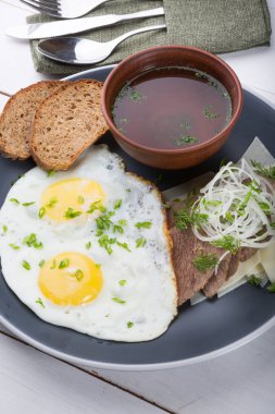 Kızarmış yumurta ekmek dilimleri, et dilimleri ve et suyu ile servis