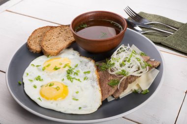 Kızarmış yumurta ekmek dilimleri, et dilimleri ve et suyu ile servis