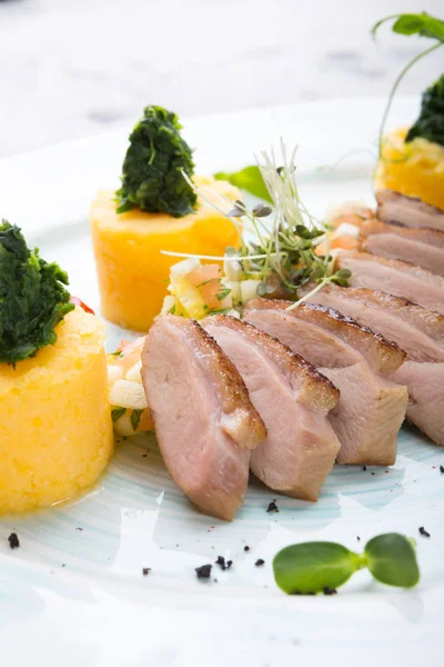 Smoked and sliced duck meat served with polenta