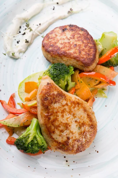 Meat cutlets served with steamed vegetables