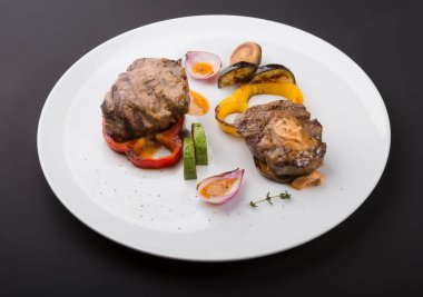 Beyaz tabakta ızgara sebzeli biftek.