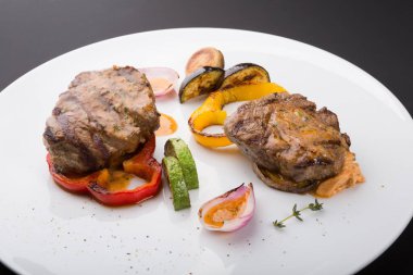 Beyaz tabakta ızgara sebzeli biftek.