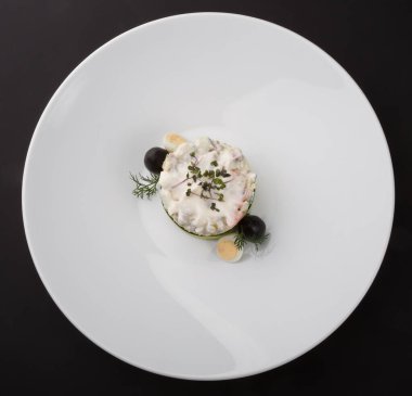 Beyaz tabakta servis edilen geleneksel Rus salatası olivieri.
